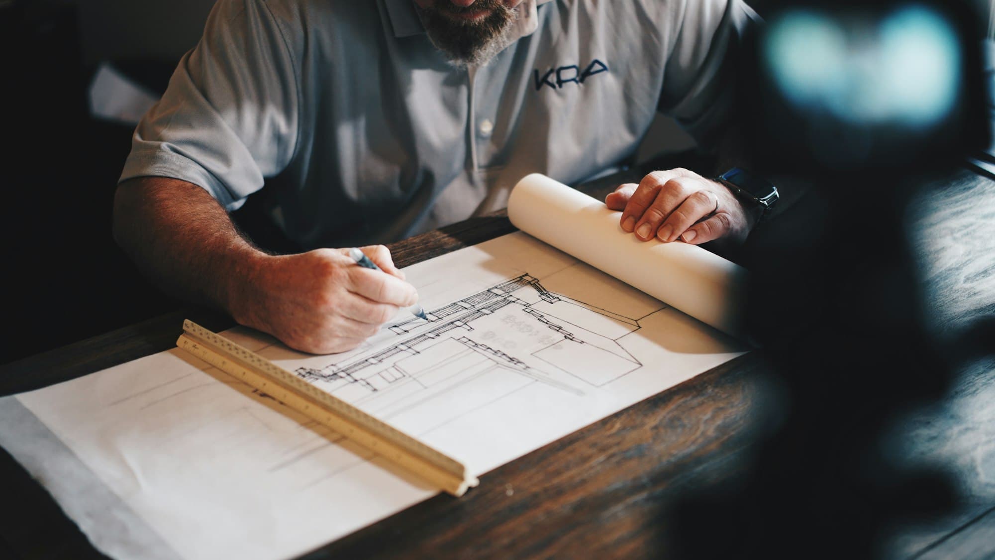 Profesional dibujando un plano sobre una mesa de trabajo