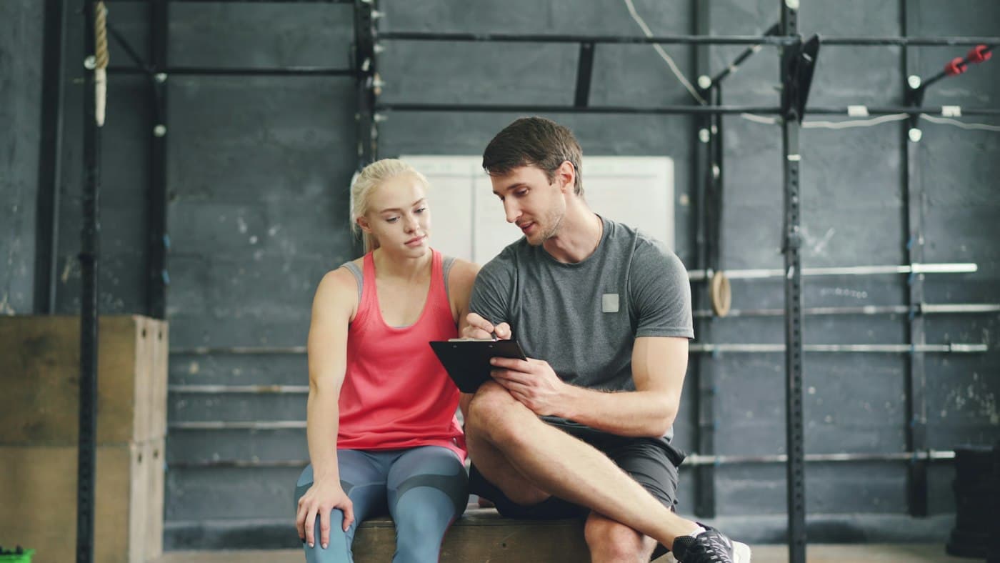 Asesor y clienta revisando un plan en una tableta dentro de un gimnasio