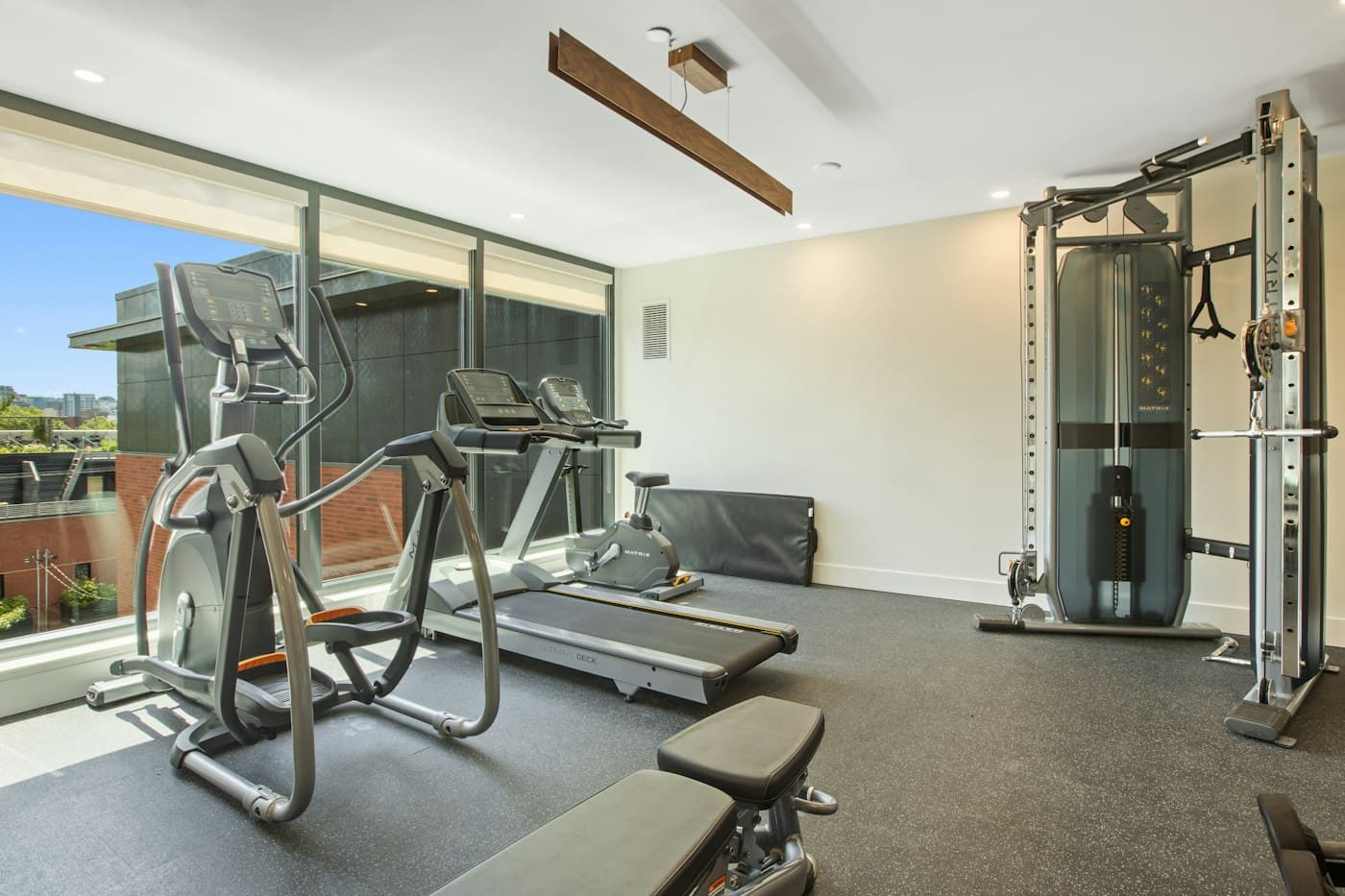 Gimnasio de conjunto residencial con elíptica, polea y ventanales